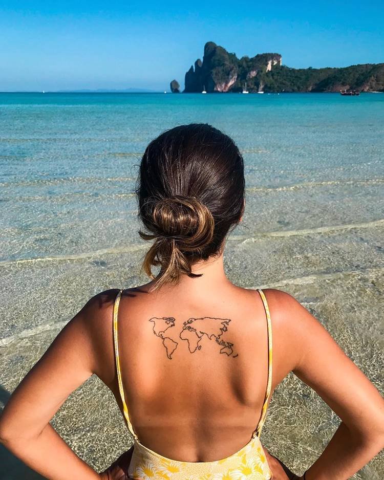 Tatuagem de mapa-múndi em costas de mulher na praia