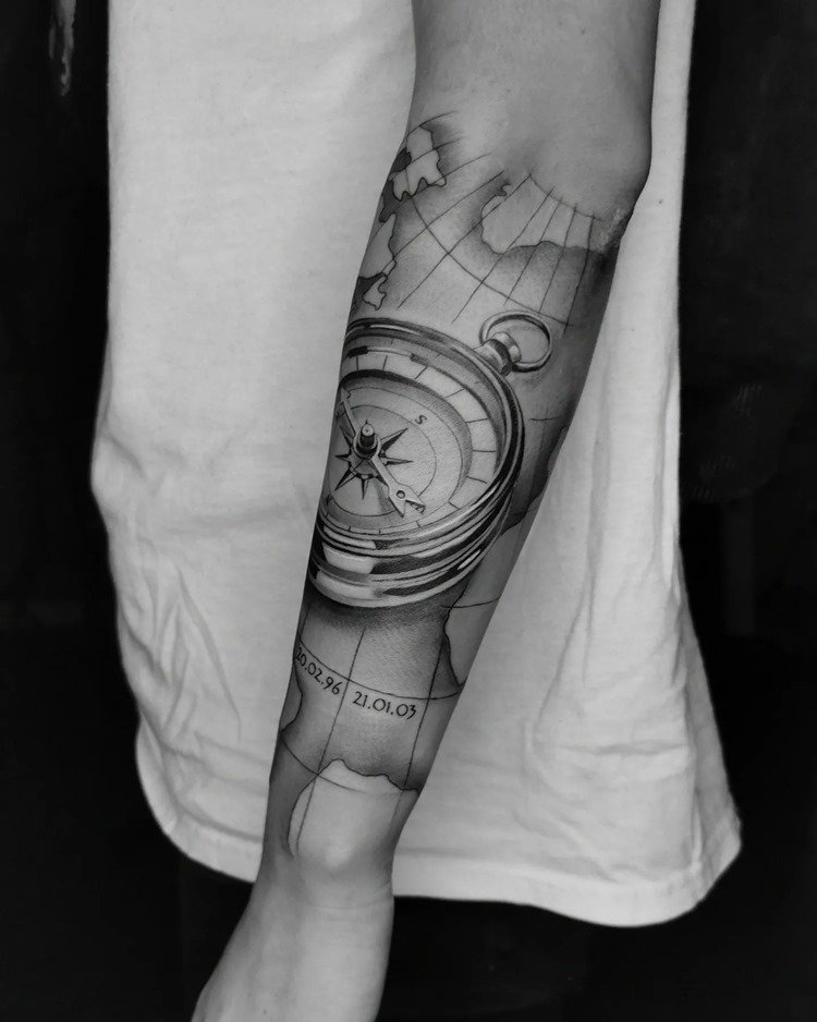 tatuagem de viagem masculina: bússola preta e branca com mapa-múndi e data