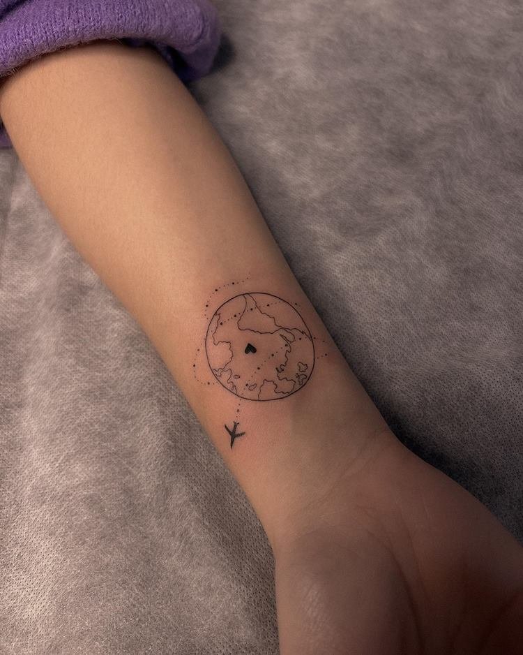 Tatuagem de viagem no braço de mundo com avião circulando