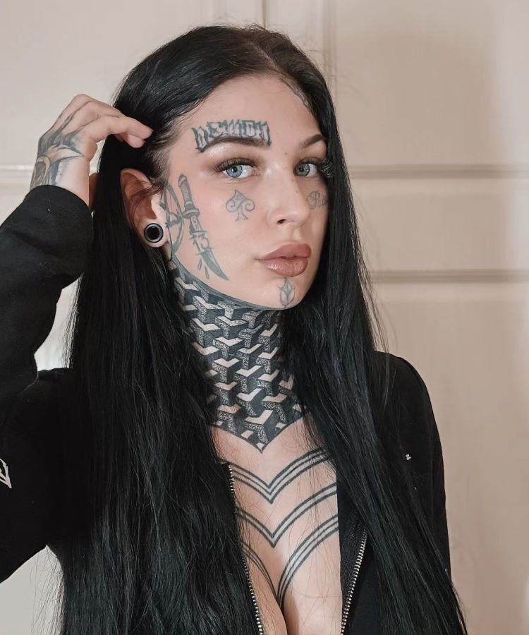 tatuagem-feminina-no-pescoco-32-1 A imagem mostra uma pessoa de costas com cabelo castanho e alargadores pretos nas orelhas. Ela tem uma tatuagem no pescoço de um design abstrato em preto, com linhas e formas geométricas que se estendem da base do crânio até os ombros. A tatuagem é complexa e artística.