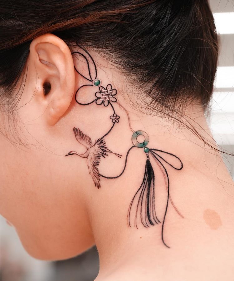 tatuagem-feminina-no-pescoco-4-1 A imagem mostra uma pessoa de perfil com cabelo preso. Ela tem uma tatuagem no pescoço de um pássaro voando, flores e linhas curvas, detalhadas em preto com pequenos pontos verdes. A tatuagem começa atrás da orelha e se estende pela lateral do pescoço.