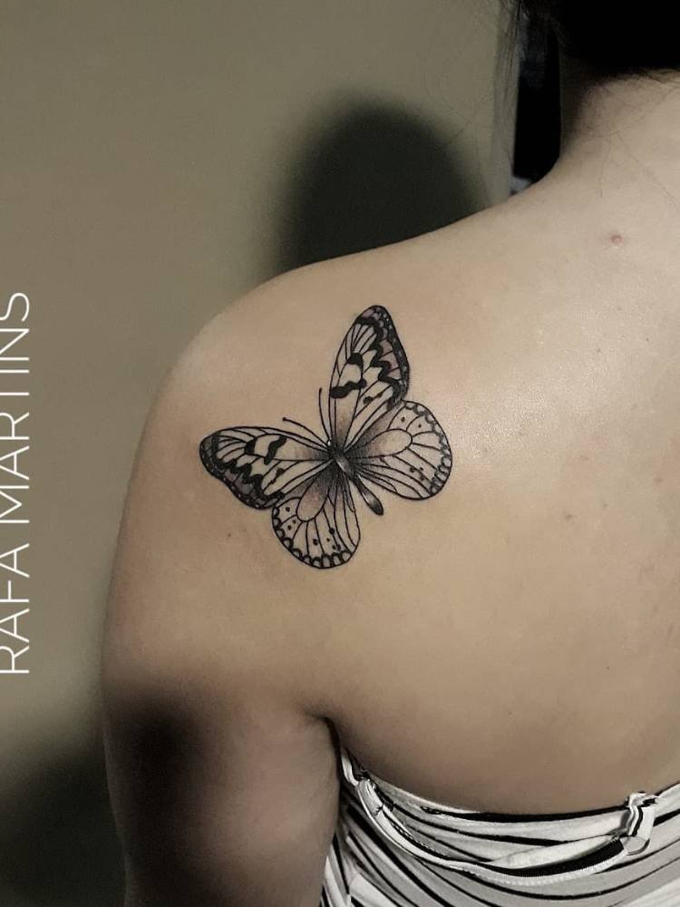 tatuagem-feminina-ombro-borboleta-atras Mulher de pele clara de costas com tatuagem de borboleta na parte inferior do ombro, com traços finos e grossos em preto