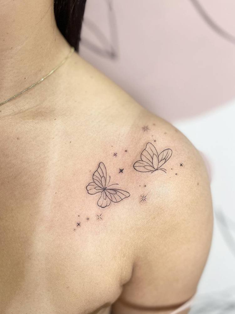 tatuagem-feminina-ombro-borboleta-delicada Mulher de pele clara com tatuagem delicada de duas borboletas e estrelas no ombro