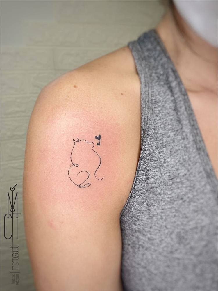 tatuagem-feminina-ombro-cachorro Mulher de pele clara e regata cinza com tatuagem no ombro de contorno fine line de cachorro