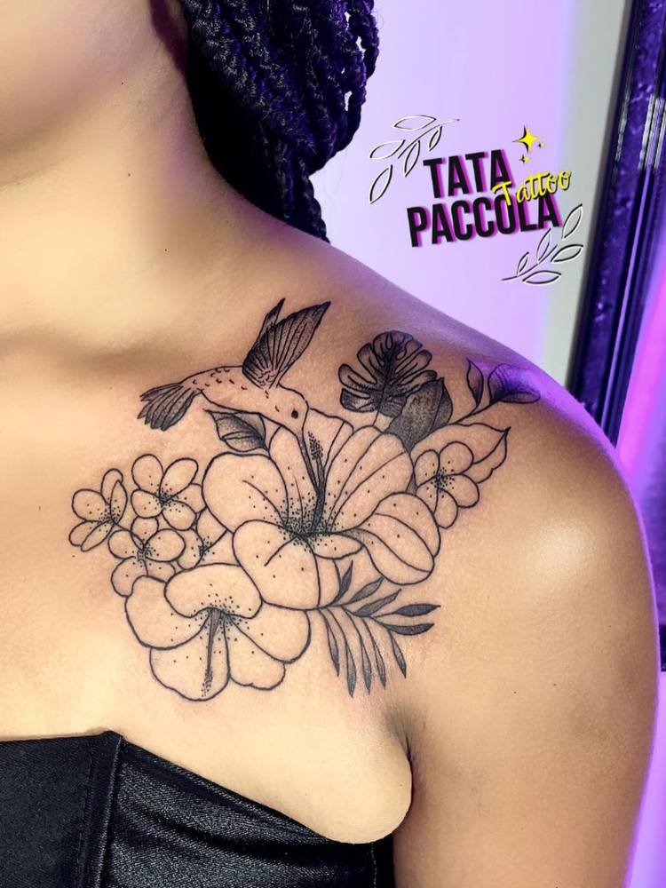 tatuagem-feminina-ombro-flor-sombra Mulher de pele morena com tatuagem de lírios, ramos e costela-de-adão sombreadas no ombro