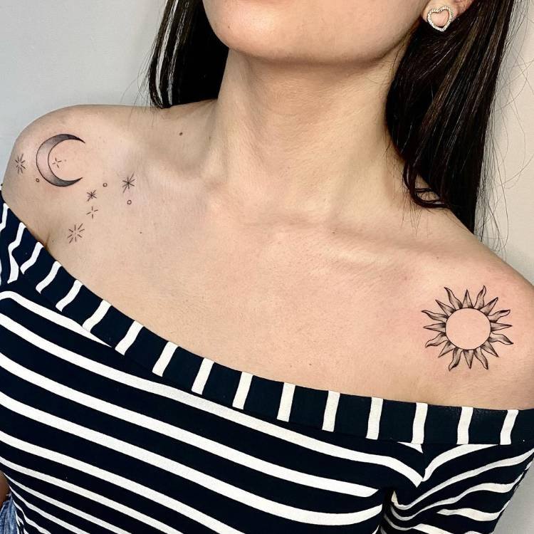 tatuagem-feminina-ombro-sol Mulher de pele clara e cabelo preto usando blusa de ombro a ombro branca e preta, com duas tatuagens, uma em cada ombro: uma de lua e outra de sol