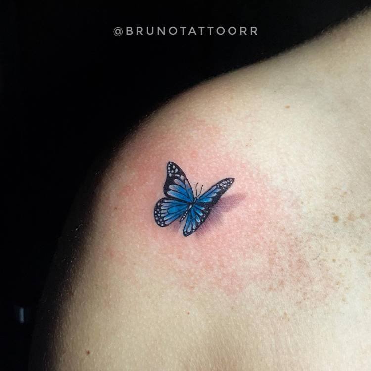 tatuagem-feminina-ombro-sombra-borboleta-azul Mulher de pele clara com tatuagem realista de borboleta azul sombreada no ombro