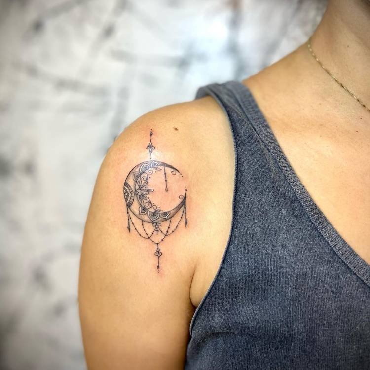 tatuagem-feminina-ombro-sombra-lua Mulher de pele clara e regata cinza com tatuagem de lua e ornamentos sombreada