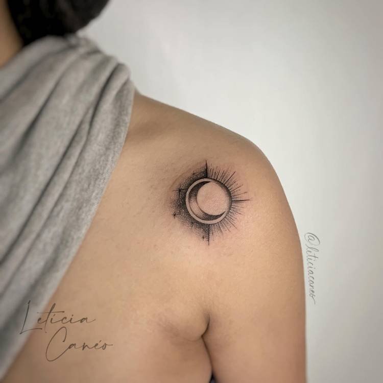tatuagem-feminina-ombro-sombra-sol-lua Mulher de pele clara com blusa cinza no pescoço e tatuagem de sol e lua, com sombras