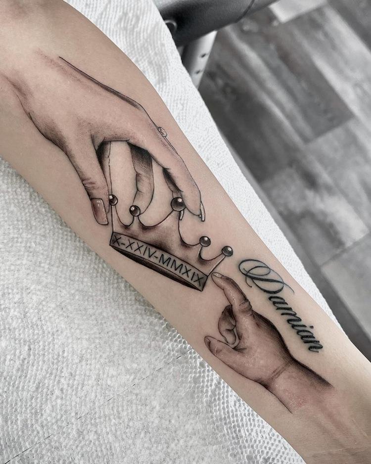 tatuagem-mae-para-filho-6 Tatuagem de mão com coroa e mão de bebê com nome de filha, cor preto