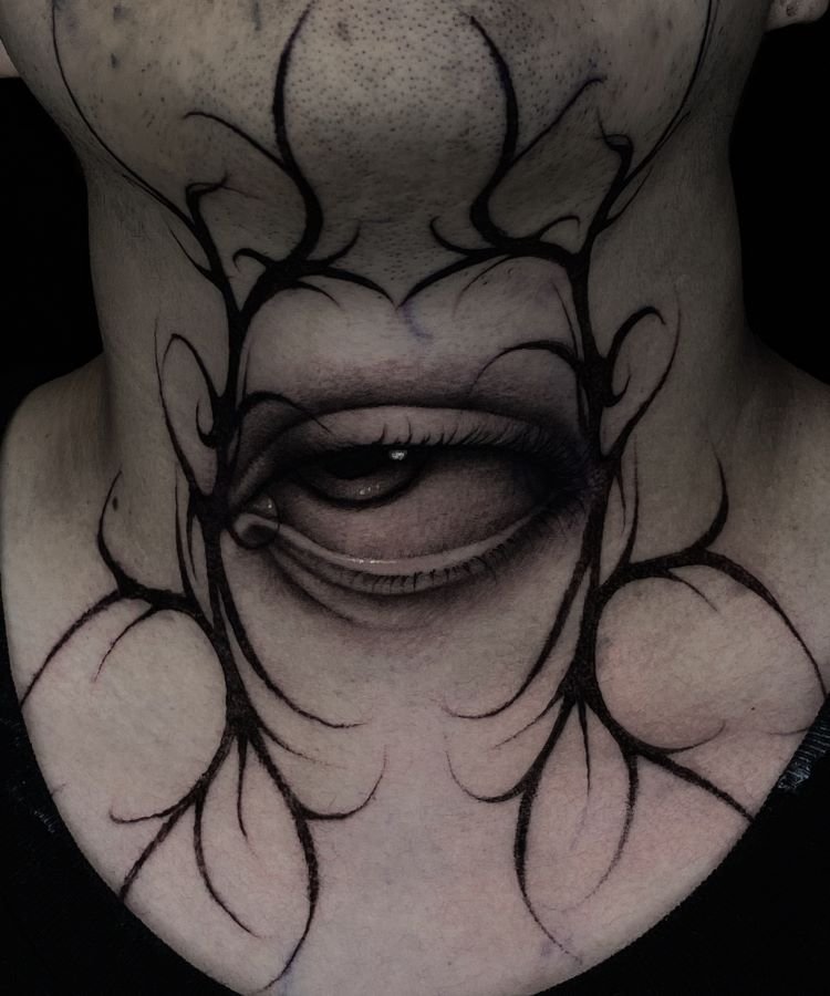 tatuagem-masculina-no-pescoco-20 A imagem mostra uma pessoa com uma tatuagem no pescoço de um olho realista, com detalhes sombreados em preto e cinza. Ao redor do olho, há linhas abstratas que se estendem pela pele. A tatuagem ocupa grande parte da frente do pescoço, criando um efeito marcante.