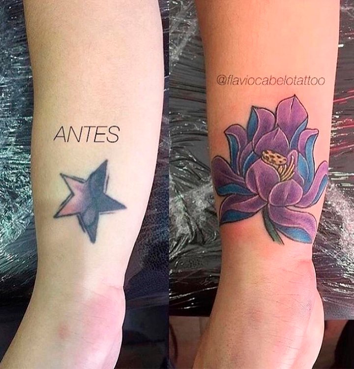 Cobertura de tatuagem antes e depois - Estrela transformada em flor de lótus Duas fotos do pulso de uma pessoa, uma foto do lado da outra. A primeira mostra uma tatuagem de uma estrela roxa e lilás com um símbolo do infinito no meio. A segunda foto é essa tatuagem coberta por outra, maior, da imagem de uma flor roxa e azul.