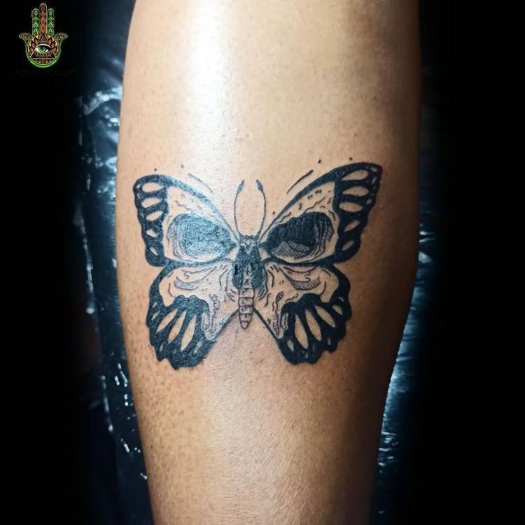 traco-grosso-caveira-borboleta-perna-1 Tatuagem de borboleta com estampa de caveira feita em traços grossos na canela de um homem de pele clara.